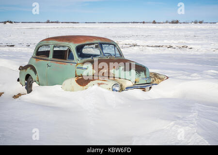 Une vieille voiture coincé dans un champ couvert de neige près de Winkler, au Manitoba, Canada. Banque D'Images