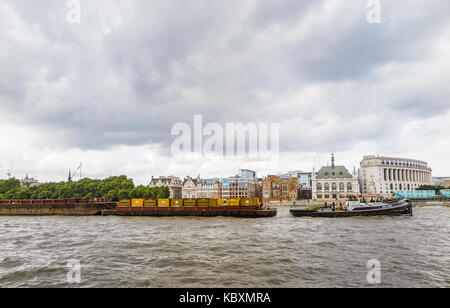 Le transport par voie navigable : Riverside CORY remorqueur de l'énergie 'Récupérer' tirant une péniche de chargement des conteneurs dans la Tamise par Victoria Embankment, London, UK Banque D'Images