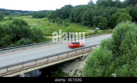 Relevé aérien de la voiture se déplace sur la serpentine. flying over red cabriolet dur la rue.Vue aérienne de la voiture rouge qui passe sur le pont. Le trafic sur le pont. Voiture rouge. Banque D'Images