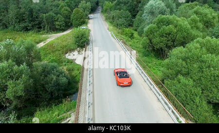 Relevé aérien de la voiture se déplace sur la serpentine. flying over red cabriolet dur la rue.Vue aérienne de la voiture rouge qui passe sur le pont. Le trafic sur le pont. Voiture rouge. Banque D'Images