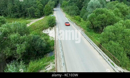 Relevé aérien de la voiture se déplace sur la serpentine. flying over red cabriolet dur la rue.Vue aérienne de la voiture rouge qui passe sur le pont. Le trafic sur le pont. Voiture rouge. Banque D'Images