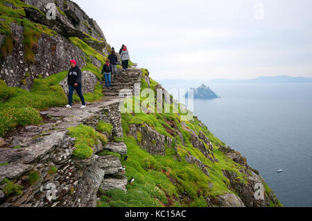 Les gens de la randonnée dans l'île de Skellig Michael (dans le backgroun peu Skellig), comté de Kerry, Irlande Banque D'Images