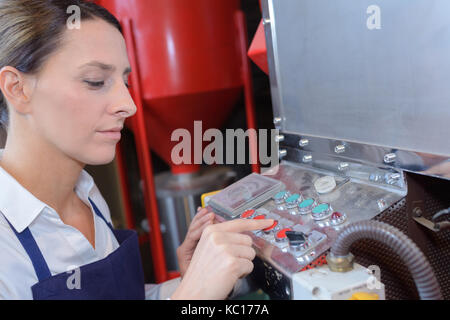 Travailleur féminin l'utilisation d'une machine dans une usine Banque D'Images