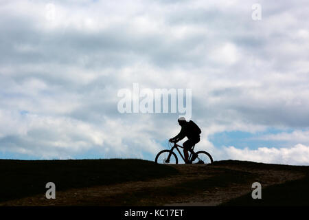 Randonnée, vélo, bicyclette, silhouette, horizon, nuages, pluie, sombre, bas, Tennyson, sentier Bridle way, bridleway, pied, chemin, sentier, de temps, de distance, de divaguer, marcheurs, sept collines, 7, l'eau douce, l'île de Wight, Angleterre, Royaume-Uni, Banque D'Images