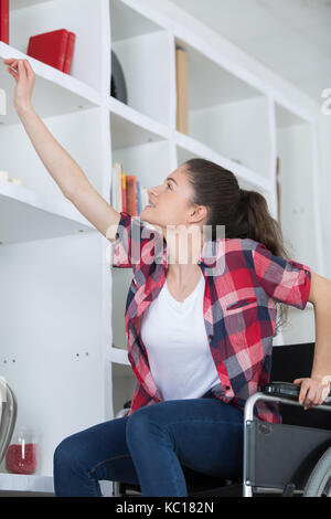 Jeune fille en fauteuil roulant vers de livre Banque D'Images