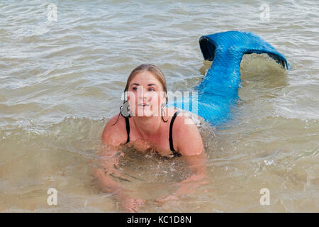 Une jeune femme vêtue comme une sirène prend un bain la mer à st.Ives en Cornouailles, Angleterre, Royaume-Uni. Banque D'Images