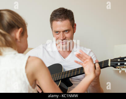 Papa joue de la guitare pour sa fille. Banque D'Images