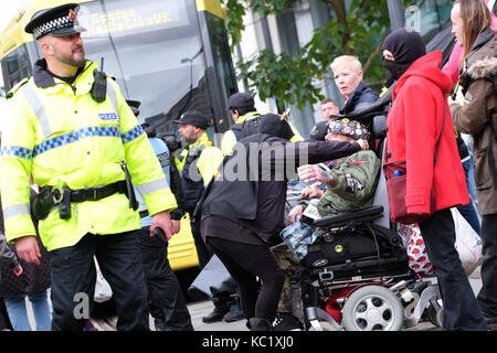 St Peters Square, Manchester, UK - Le dimanche 1er octobre 2017 - gouvernement un manifestant dans un fauteuil roulant bénéficie du soutien d'un autre manifestant tout en empêchant le réseau de tramway dans le centre-ville de Manchester - Police préparer pour effacer les manifestants devant la conférence du parti conservateur. Photo Steven Mai / Alamy Live News Banque D'Images