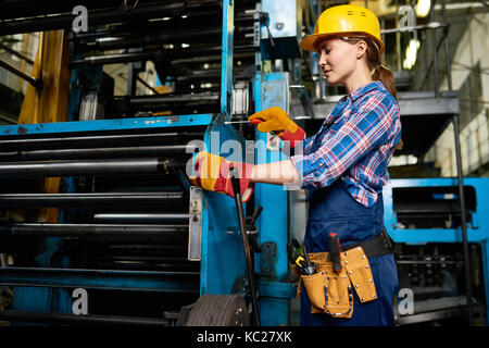 Vue de côté portrait de femme employée d'usine mise en place d'unités de la machine dans l'usine moderne Banque D'Images