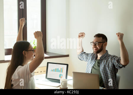 Trouver un concept de solution. two businesspeople passant des armes en remportant le geste, l'augmentation des stats sur leur ordinateur portable. Banque D'Images