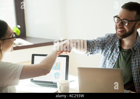 La célébration de travail bien fait. two businesspeople fist bumping en remportant le geste, l'augmentation des stats sur leur ordinateur portable. Banque D'Images