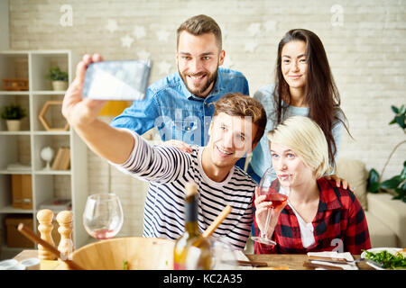 Portrait of happy friends at dinner table selfies tout en célébrant l'occasion festive Banque D'Images