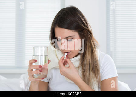 Portrait de jeune femme prendre des pilules avec un verre d'eau Banque D'Images