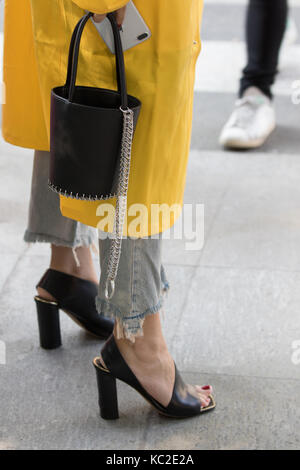 Milan, Italie - 22 septembre 2017 : modèle portant un sac noir et un manteau jaune pendant la parade armani, photographié dans la rue Banque D'Images