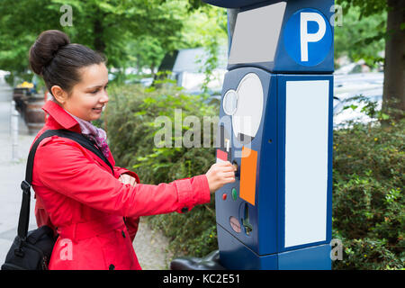 Jeune femme belle l'insertion d'une pièce de monnaie pour Parking Meter Banque D'Images