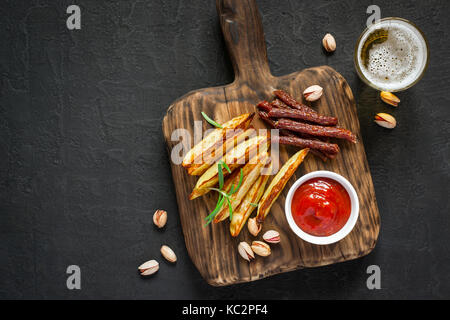 Des collations variées pour la bière. Pommes de terre rissolées pepperoni les noix et un verre de bière. Banque D'Images