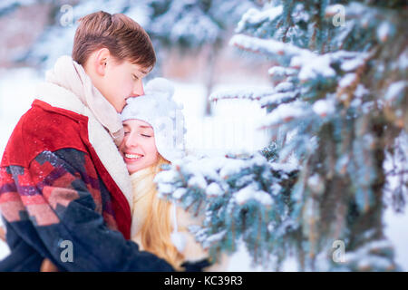 Jeune couple hugging on snow in winter park. Banque D'Images