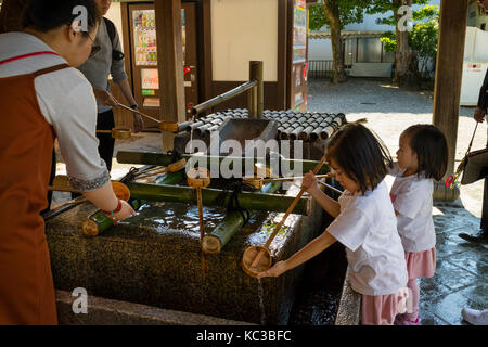 Kyoto, Japon - 18 mai 2017 : les enfants se laver les mains à un purificaton avant d'entrer dans le temple du bassin Banque D'Images