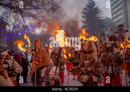 Pernik, Bulgarie - 27 janvier 2017 : les participants masqués dans scary costumes de fourrure et des masques en bois avec des cornes sont maintenant en marchant torches brûlant Banque D'Images