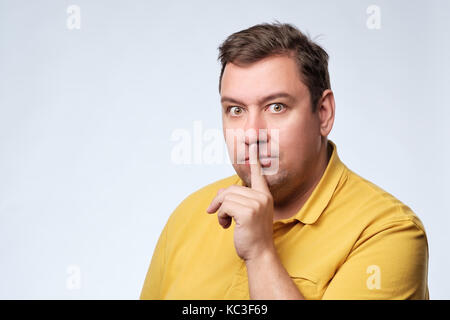 Doigt sur lèvres comme man gesturing shh sign Banque D'Images