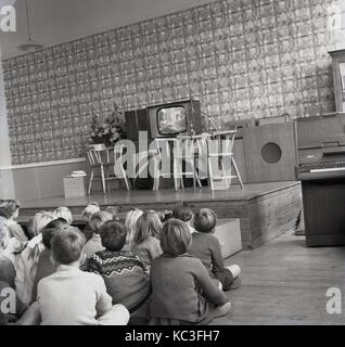 1964, historiques, groupes d'enfants de l'école primaire s'asseoir ensemble à regarder un programme pour enfants sur un nouveau téléviseur. c'est à cette époque que la programmation pour enfants a été diffusé pour la première fois au Royaume-Uni et les radiodiffuseurs ont donné de nouveaux téléviseurs pour encourager l'affichage. Banque D'Images