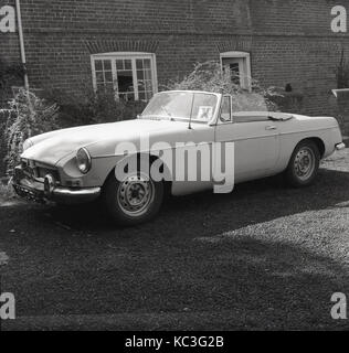 1963, historiques, une voiture de sport de la BTP avec hors de moyeux de roues stationné à l'extérieur d'une maison avec la lettre X bloqué sur la fenêtre, England, UK. Banque D'Images