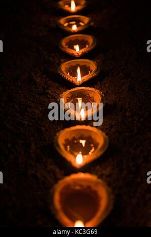 Happy diwali - nombreux diya en terre cuite ou lampes à huile disposées sur surface de l'argile ou la masse dans une ligne ou courbe ou forme de zigzag, selective focus Banque D'Images