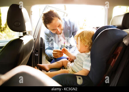 Père de mettre son fils dans la voiture. Banque D'Images