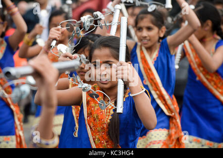 Danseurs et musiciens du temple swaminarayan cardiff jouer l'instrument traditionnel lezim alors qu'il traite de l'inauguration d'une statue du mahatma Gandhi dans la baie de Cardiff, Pays de Galles, pour marquer le jour de sa naissance en 1869, et la Journée internationale de la non-violence qui est également célébrée le 2 octobre. Banque D'Images