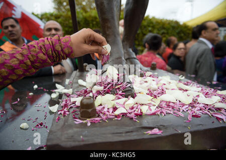 Personnes réparties pétales de fleurs au pied d'une statue du mahatma Gandhi, c'est dévoilé dans la baie de Cardiff, Pays de Galles, pour marquer le jour de sa naissance en 1869, et la Journée internationale de la non-violence qui est également célébrée le 2 octobre. Banque D'Images