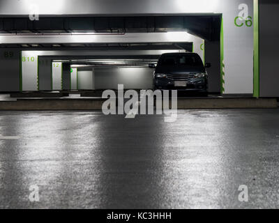 La voiture grise garée dans le parking. Le parking est sombre et solitaire dans le centre commercial. Banque D'Images