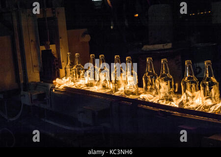 Usine de fabrication de bouteilles en verre. les bouteilles de verre sur un convoyeur à courroie avec le feu Banque D'Images