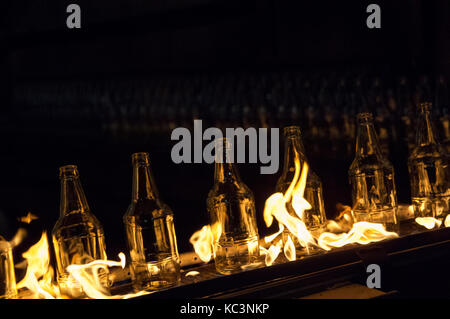 Usine de fabrication de bouteilles en verre. les bouteilles de verre sur un convoyeur à courroie avec le feu Banque D'Images