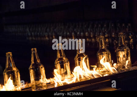 Usine de fabrication de bouteilles en verre. les bouteilles de verre sur un convoyeur à courroie avec le feu Banque D'Images