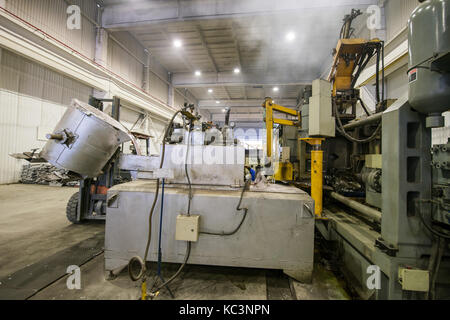 Verser le métal aluminium à partir de la louche pour le chargement de la machine dans un grand récipient Banque D'Images