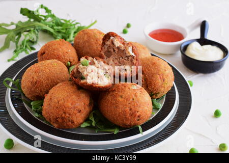 Boules de poisson avec du thon et les pois verts sur une plaque noire sur fond blanc. la saine alimentation concept. Banque D'Images