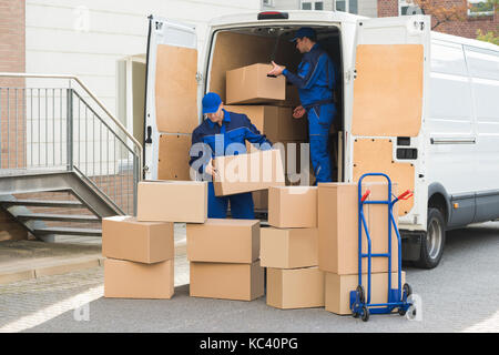 Les jeunes hommes de livraison de boîtes en carton de déchargement camion sur street Banque D'Images