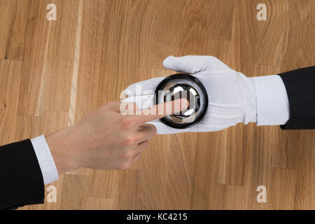 Portrait of businessman ringing service bell en tenue par chasseur au comptoir d'accueil Banque D'Images