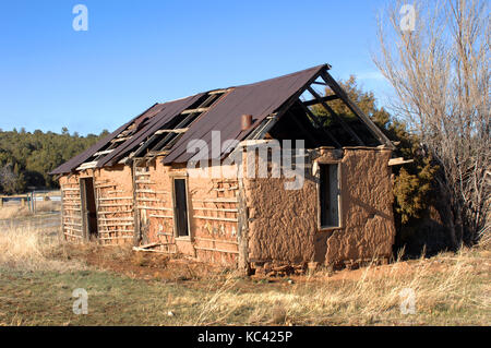 Vieux bâtiment d'adobe s'écroule en ruine. depuis longtemps abandonnées, supports en bois à travers la détérioration des murs en adobe. portes et fenêtres vides. Banque D'Images