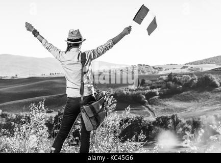 Découvrir une vue magique de la toscane. vu de dos jeune femme avec sac randonneur sur toscane randonnée pédestre avec drapeau italien réjouissance Banque D'Images