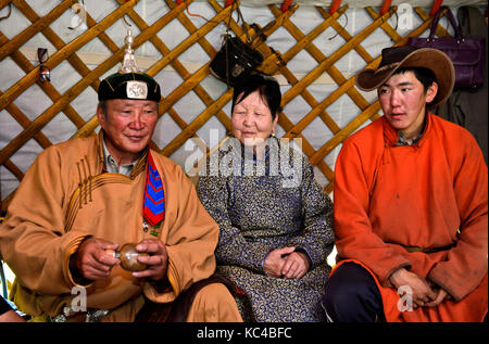 Dans la maison de bergers mongols, père, mère et fils dans une yourte traditionnelle, l'homme tenant une bouteille de tabac à priser traditionnel, huurug, dans ses mains, mongo Banque D'Images