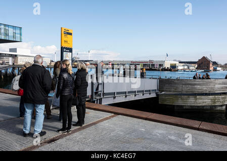 Un groupe de touristes attendant l'arrivée du bus jaune du port de Copenhague (Københavns Hannebusser) qui dessert la longueur du Copenhague Banque D'Images