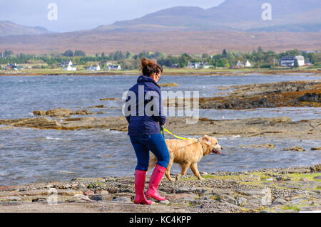 Isle of Skye, Scotland, UK. 2Nd Oct, 2017. Météo France : une femme en rouge Wellington promenades son chien sur l'ancienne jetée à Broadford. Le Met Office ont émis un avertissement jaune de vent et pluie pour la plupart de l'Écosse. Credit : Skully/Alamy Live News Banque D'Images