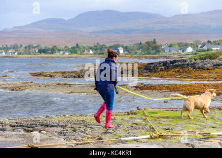 Isle of Skye, Scotland, UK. 2Nd Oct, 2017. Météo France : une femme en rouge Wellington promenades son chien sur l'ancienne jetée à Broadford. Le Met Office ont émis un avertissement jaune de vent et pluie pour la plupart de l'Écosse. Credit : Skully/Alamy Live News Banque D'Images