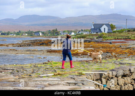 Isle of Skye, Scotland, UK. 2Nd Oct, 2017. Météo France : une femme en rouge Wellington promenades son chien sur l'ancienne jetée à Broadford. Le Met Office ont émis un avertissement jaune de vent et pluie pour la plupart de l'Écosse. Credit : Skully/Alamy Live News Banque D'Images