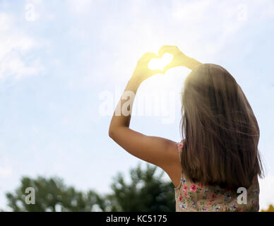 Girl holding hands in heart shape Banque D'Images