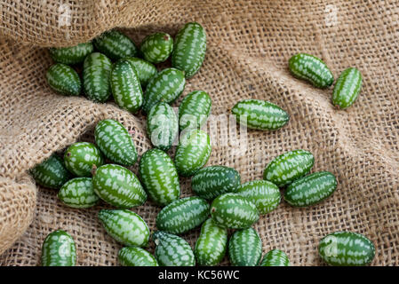 Cucamelon fruits, également connu sous le nom de cornichons aigre mexicain Mexicain, concombres Melothria scabra, ou sur un sac de toile de jute, contexte Banque D'Images