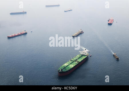 Les navires dans le détroit de Singapour à partir de la hauteur. grande citerne avec deux plates-formes d'hélicoptères rester sur l'ancre et attendre leur tour pour entrer dans le port pour u Banque D'Images