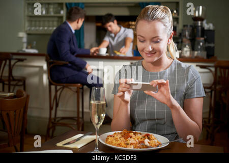 La prise de photo de blogger nourriture repas restaurant on mobile phone Banque D'Images