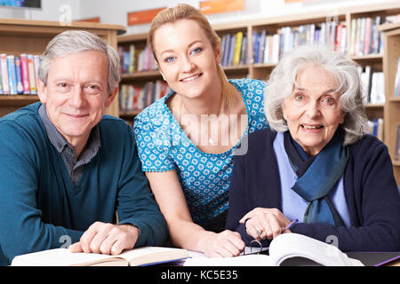 Portrait d'étudiants adultes travaillant avec l'enseignant dans la bibliothèque Banque D'Images